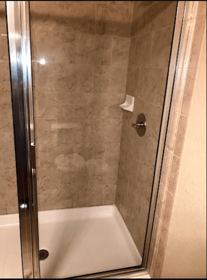 Modern glass shower enclosure featuring beige tiled walls and a white base, showcasing a minimalist bathroom design.