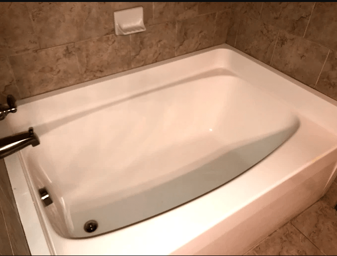 Freestanding white bathtub in a tiled bathroom, highlighting its clean lines and modern design, ideal for promoting relaxation and luxury.