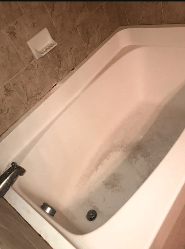 A clean, white bathtub partially filled with water, set against a tiled wall, suggesting a space for relaxation or bathing.