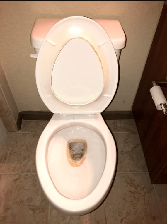 A dirty toilet bowl with brown stains and bubbling water, highlighting poor cleanliness in a bathroom setting. Relevant for discussions on hygiene standards.